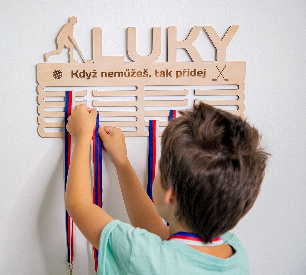 Dítě věší medaili na personalizovaný dřevěný věšák